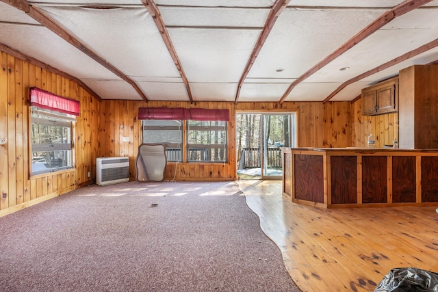 unfurnished living room with heating unit, beamed ceiling, and wooden walls