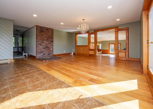 empty room featuring light wood finished floors, recessed lighting, baseboard heating, an inviting chandelier, and baseboards