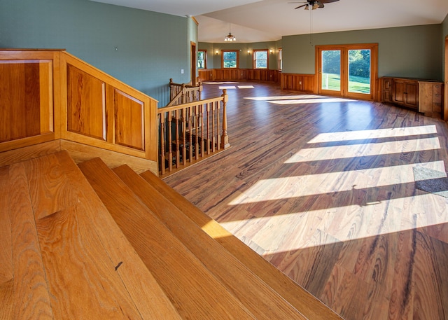 interior space with wainscoting, lofted ceiling, ceiling fan, wood finished floors, and french doors