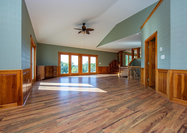 spare room with lofted ceiling, stairway, wainscoting, ceiling fan, and wood finished floors