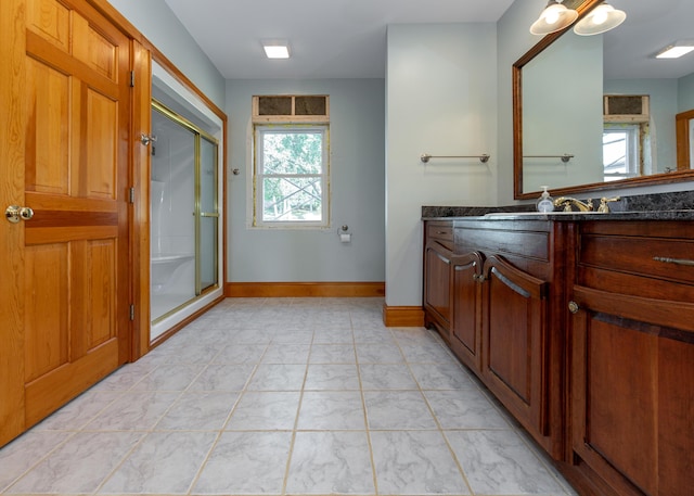 full bath featuring a stall shower, vanity, and baseboards