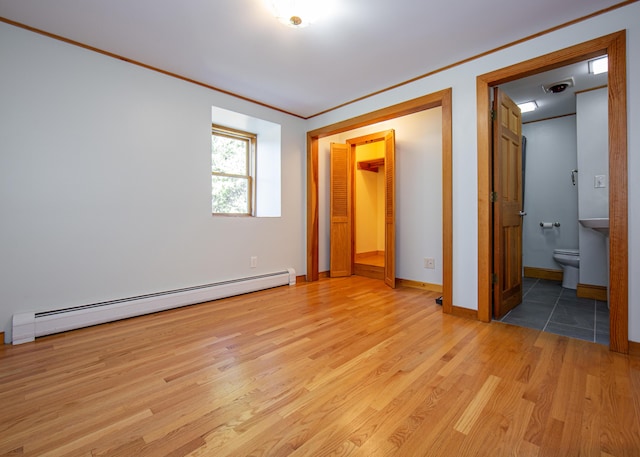 unfurnished bedroom with crown molding, light wood-style flooring, baseboard heating, ensuite bath, and baseboards