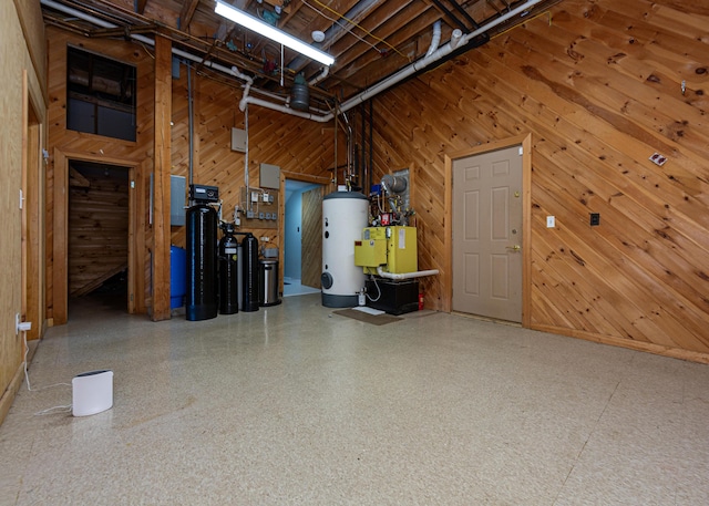 garage featuring wood walls, water heater, and a heating unit