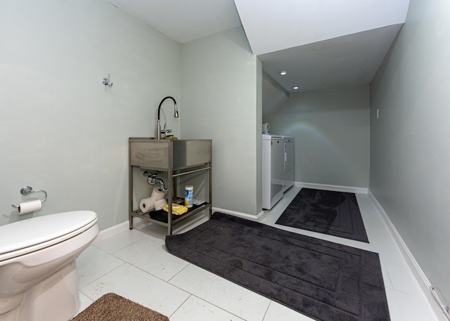 bathroom featuring baseboards, toilet, washing machine and clothes dryer, tile patterned flooring, and a sink