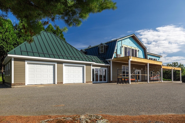 exterior space with driveway, a standing seam roof, metal roof, and a gambrel roof