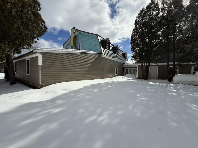 snow covered property with a garage and a gambrel roof