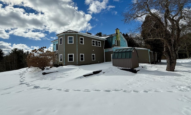 snow covered house with a storage shed and an outbuilding