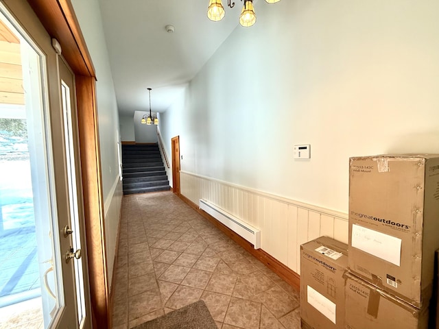 corridor featuring stairs, wainscoting, light tile patterned floors, and a baseboard radiator