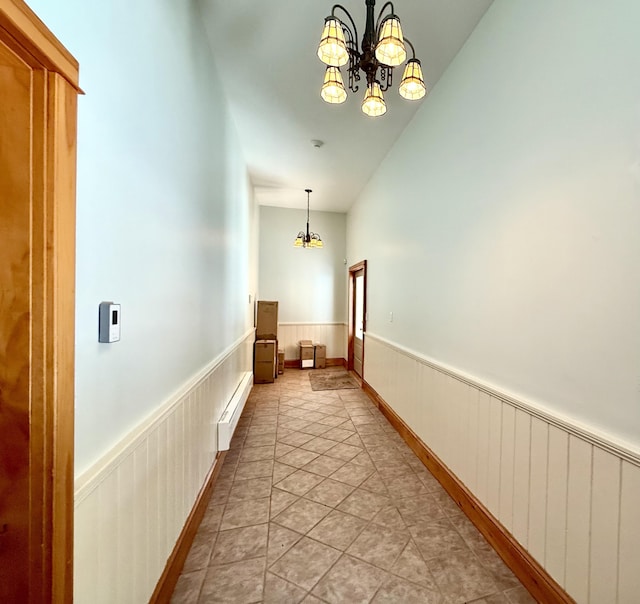 hallway featuring baseboard heating, a notable chandelier, and wainscoting