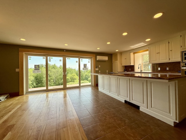 547 Mariaville Rd, Ellsworth, ME 04605 - kitchen featuring a wall mounted air conditioner, recessed lighting, white cabinets, dark countertops, and backsplash