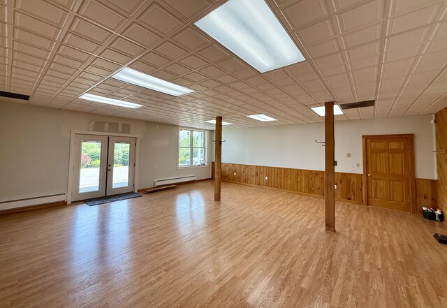 547 Mariaville Rd, Ellsworth, ME 04605 - unfurnished room with baseboard heating, light wood finished floors, a wainscoted wall, wooden walls, and french doors