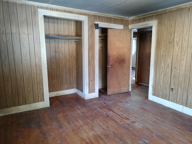 unfurnished bedroom featuring wood-type flooring, wood walls, and baseboards