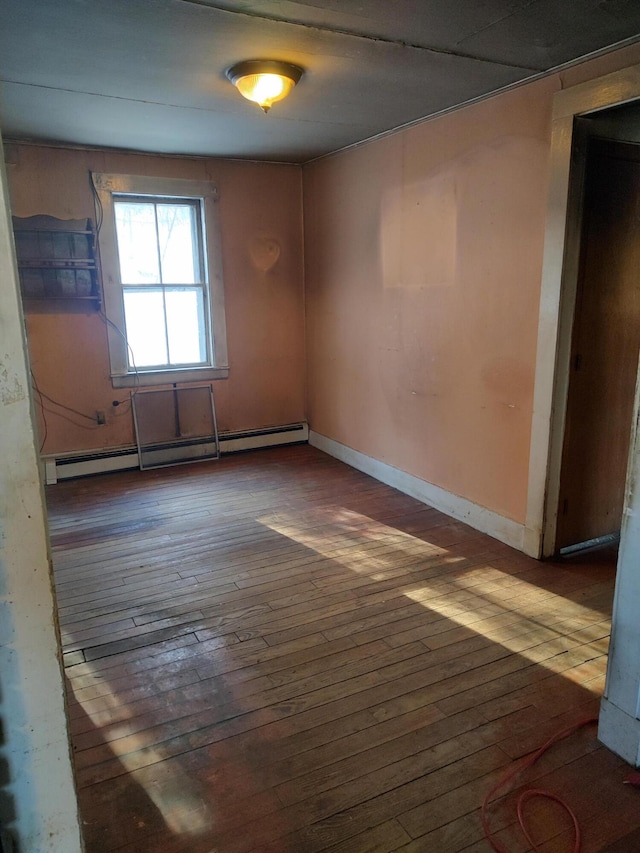 unfurnished room with a baseboard radiator, hardwood / wood-style flooring, and baseboards