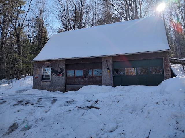 snow covered garage featuring a detached garage