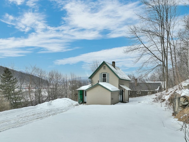 view of snowy exterior with a garage and a chimney