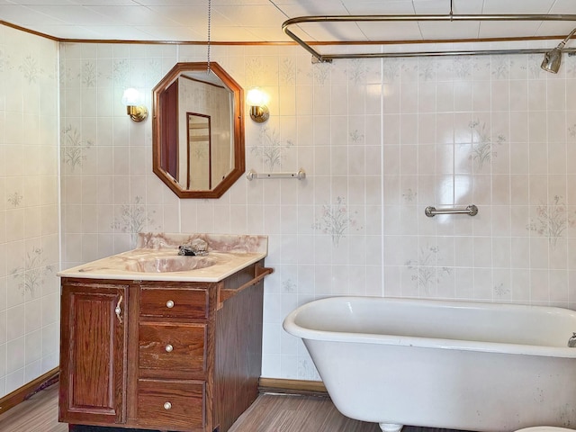 bathroom with a freestanding bath, vanity, and tile walls