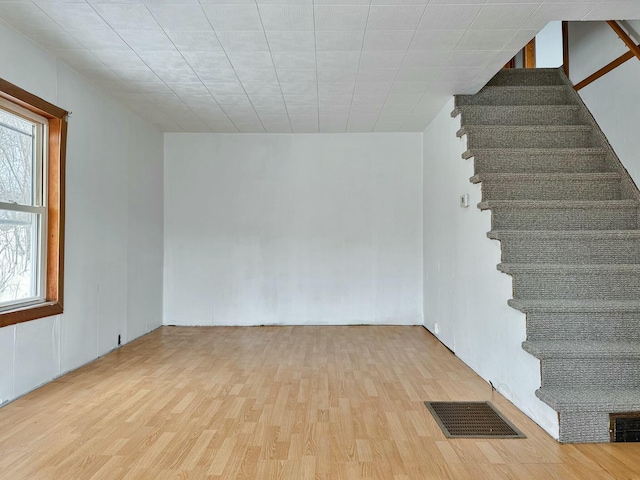 unfurnished room featuring stairway, wood finished floors, and visible vents