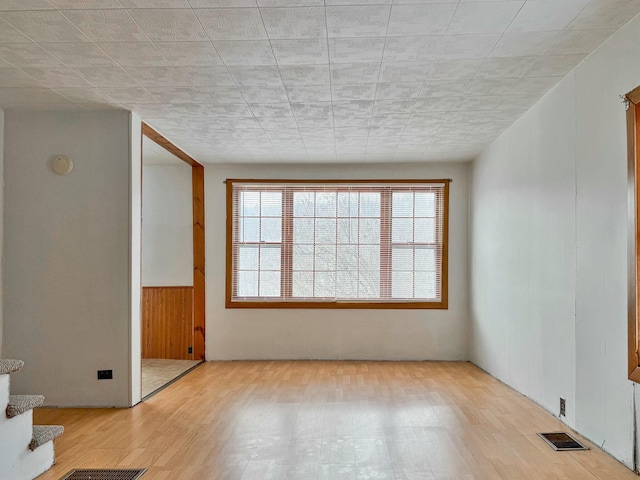 unfurnished room featuring stairs, visible vents, and wood finished floors