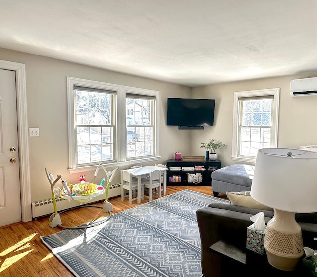 living room featuring plenty of natural light, a wall mounted AC, a baseboard radiator, and wood finished floors