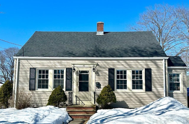 view of front of house with a shingled roof and a chimney