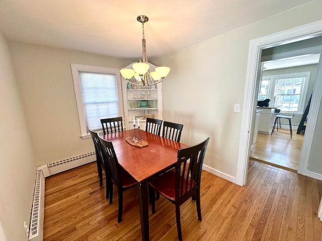 dining area featuring a baseboard heating unit, light wood-type flooring, baseboards, and an inviting chandelier