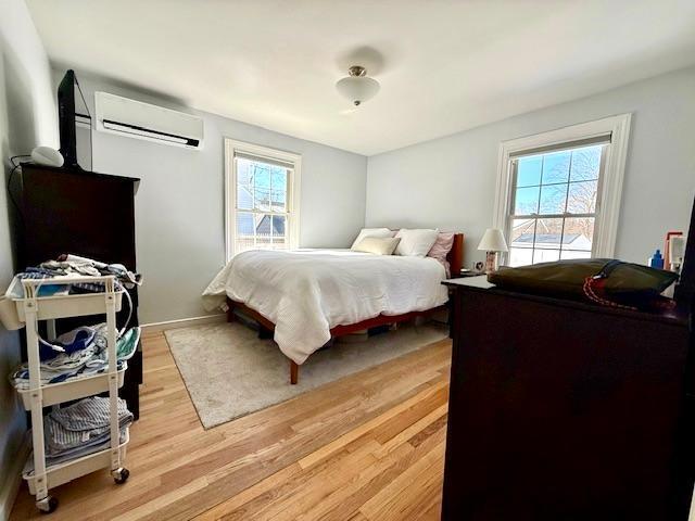 bedroom featuring light wood-type flooring and a wall unit AC