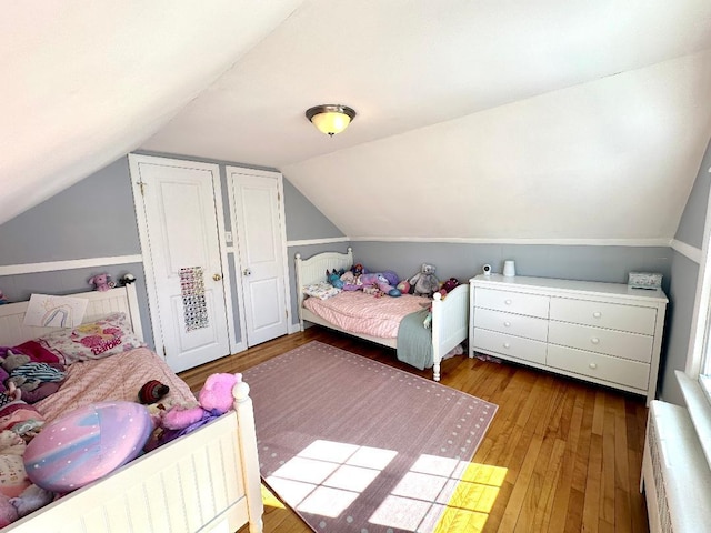 bedroom with radiator, wood-type flooring, and vaulted ceiling