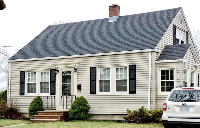 cape cod-style house with a shingled roof and a chimney