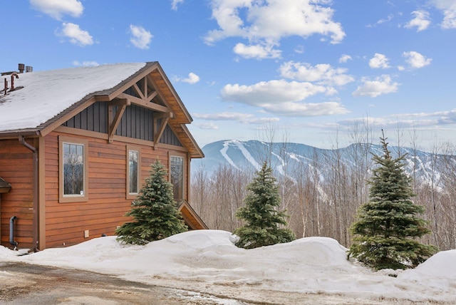 view of snowy exterior featuring board and batten siding and a mountain view