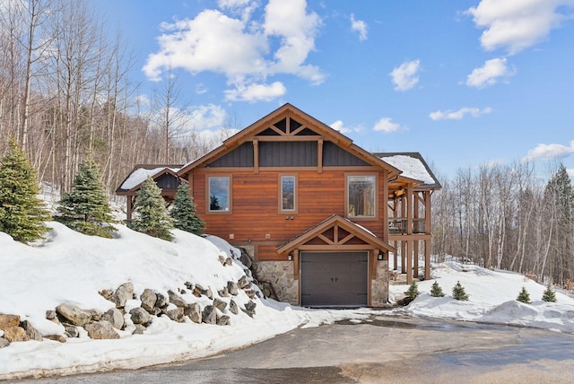 rustic home with driveway, stone siding, an attached garage, and board and batten siding