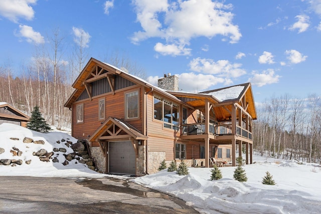 rustic home featuring stone siding, a chimney, an attached garage, and board and batten siding