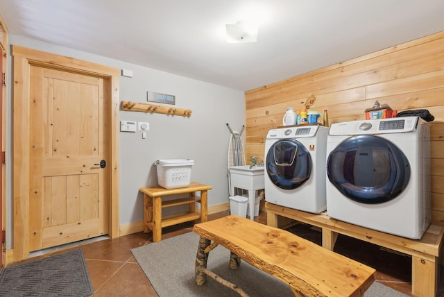 laundry room with a sink, wooden walls, separate washer and dryer, tile patterned flooring, and laundry area