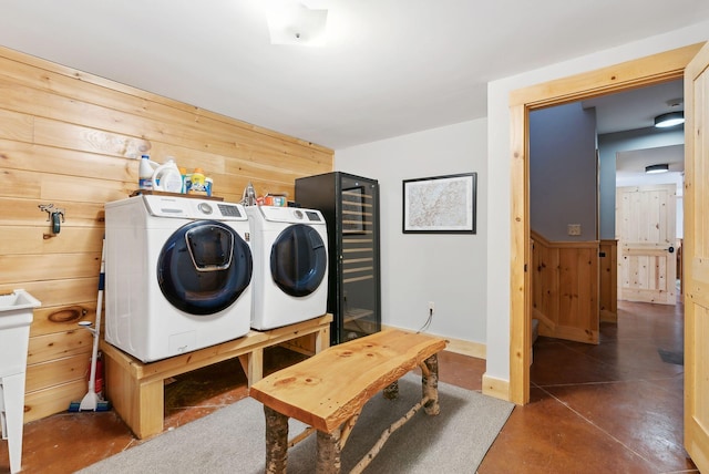 laundry room featuring washing machine and dryer, laundry area, wood walls, and baseboards