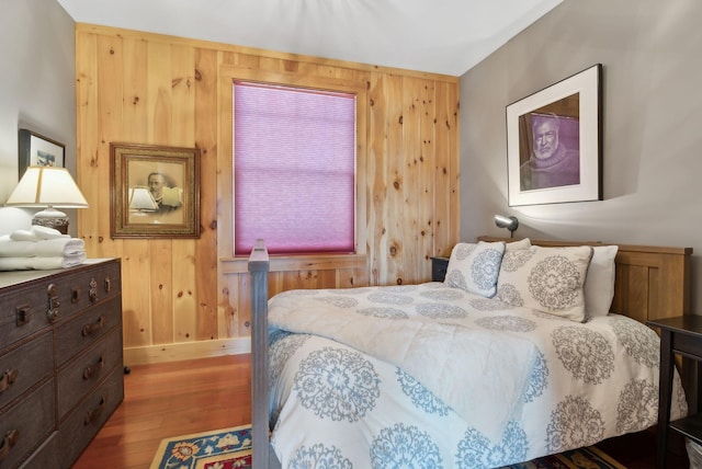 bedroom with wood walls, baseboards, and wood finished floors