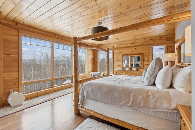 bedroom with wood ceiling, multiple windows, wood-type flooring, and wooden walls