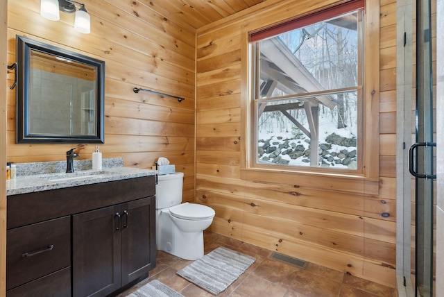 bathroom with visible vents, toilet, tile patterned floors, vanity, and wood walls