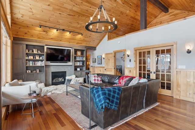 living area with a fireplace, wood finished floors, wood ceiling, french doors, and wainscoting