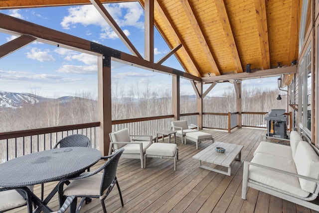 sunroom featuring lofted ceiling with beams, wooden ceiling, a mountain view, and a wealth of natural light