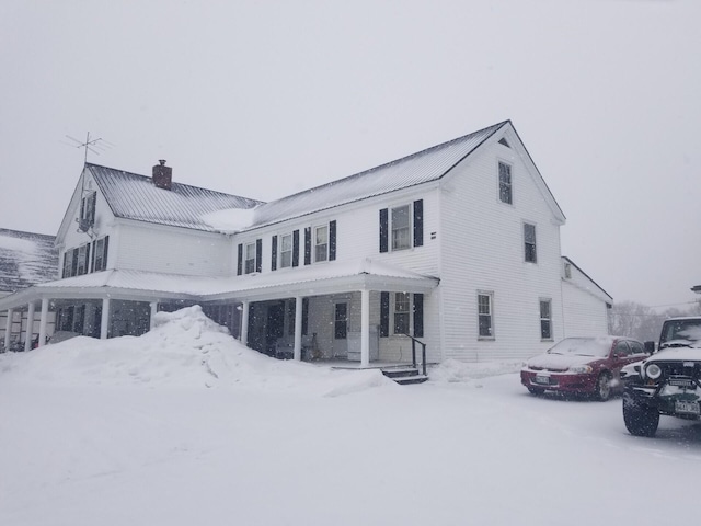 snow covered house with a chimney and metal roof