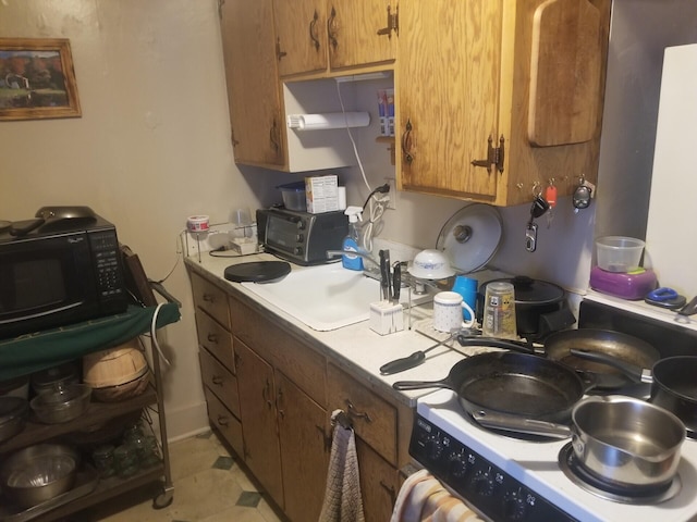 kitchen featuring brown cabinets, black microwave, light countertops, and a sink