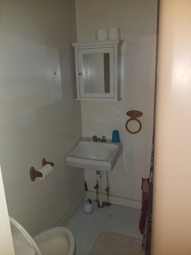 bathroom featuring baseboards, a sink, and toilet