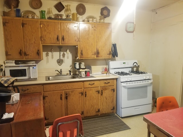 kitchen featuring brown cabinetry, white appliances, light countertops, and a sink