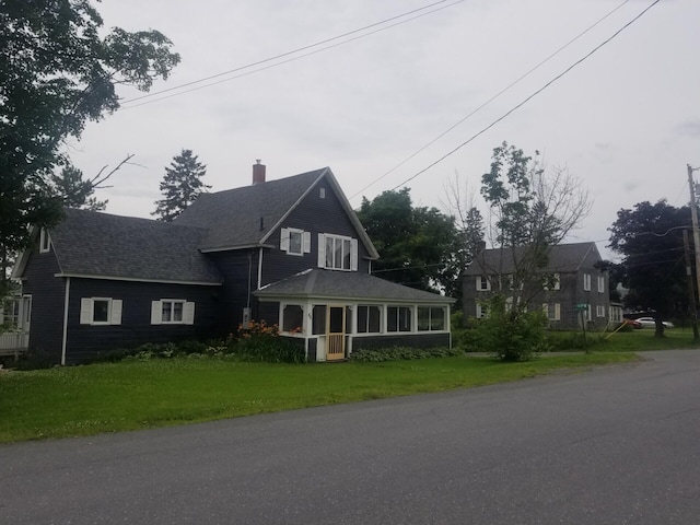 view of front of property with a front lawn, a chimney, and a shingled roof