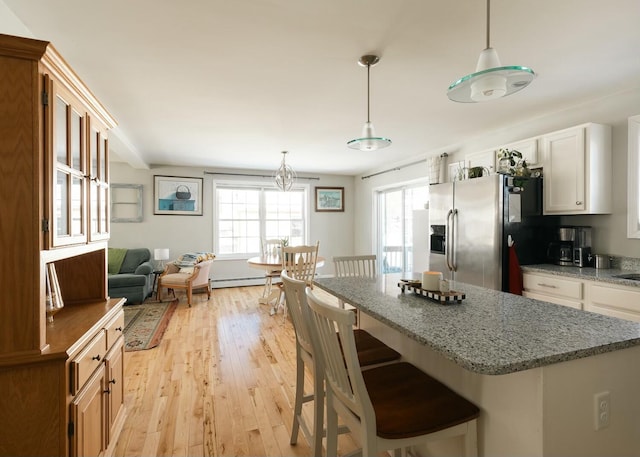 kitchen featuring a baseboard heating unit, a kitchen island, light wood-type flooring, stainless steel fridge with ice dispenser, and a kitchen bar