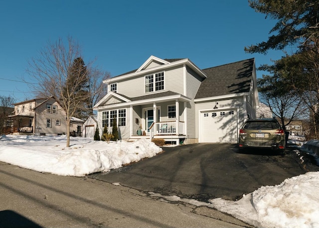 traditional home featuring a porch, roof with shingles, a garage, and aphalt driveway