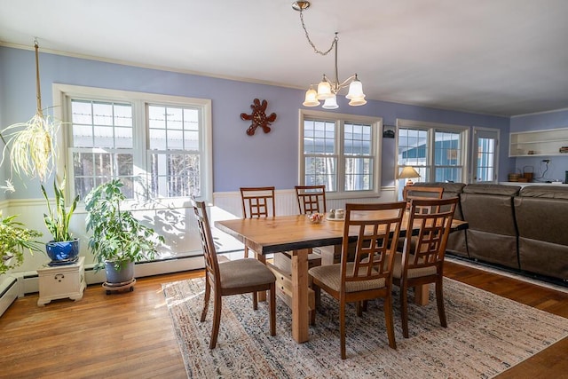 dining space featuring ornamental molding, a notable chandelier, and wood finished floors