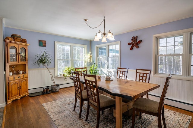 dining area with ornamental molding, wainscoting, dark wood finished floors, and an inviting chandelier