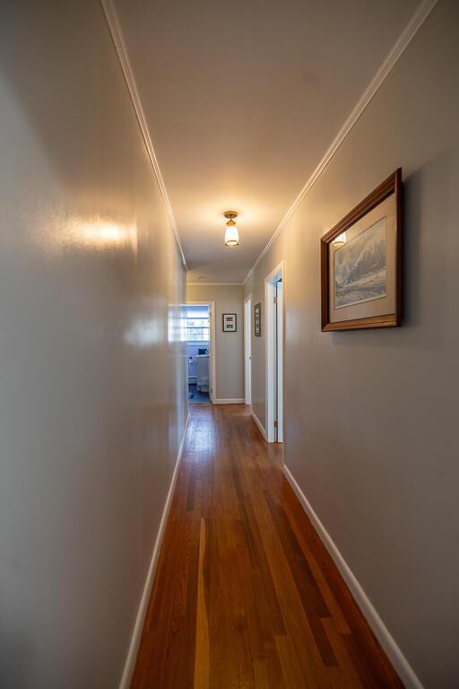 hall featuring baseboards, dark wood-type flooring, and crown molding