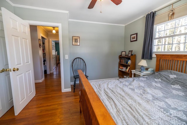 bedroom featuring a ceiling fan, crown molding, baseboards, and wood finished floors