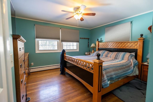 bedroom featuring ornamental molding, baseboard heating, wood finished floors, and a ceiling fan